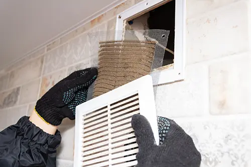 A professional repairman removes a dirty air filter in a home in Branson, MO.