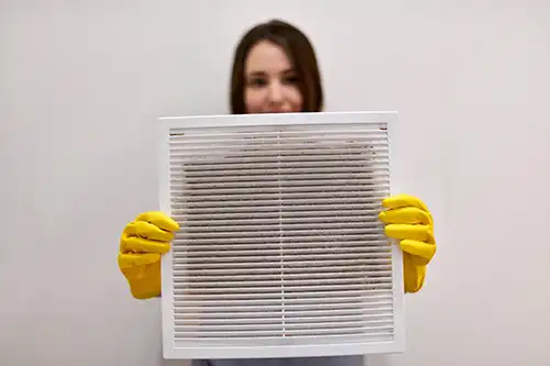 Sho-Me Clean Duct Cleaning—Woman holding dirty and dusty ventilation grille from a home in Branson, MO.