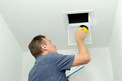 Sho-Me Clean Duct Cleaning—A man checks the air ducts in a home in Branson, MO and prepares to change the filter.